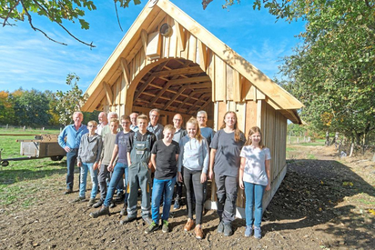 Steht: Die acht Achtklässler der MKG vor der Weidehütte, die sie in der Projektwoche am Kanal errichtet haben, mit Anleitern und Unterstützern. Foto: Alfred Riese