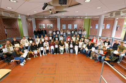 In Wirklichkeit sind es mehr: Ein Teil der Schülerinnen und Schüler, die für besondere Leistungen von der MKG ausgezeichnet wurden, nahm die Urkunden am Donnerstag im kleinen Forum entgegen, ein Teil hat sie schon, ein weiterer Teil bekam sie mitgebracht. Oben links stehen Fachlehrerinnen und Schulleiter Maarten Willenbrink. (Foto: Alfred Riese)