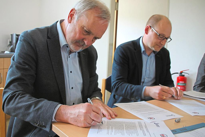 Wilfried Roos als Vorsitzender des Fördervereins Klimakommune Saerbeck und Maarten Willenbrink, kommissarischer Leiter der Maximilian-Kolbe-Gesamtschule, unterzeichnen die sechs Punkte starke Vereinbarung. Foto: Jan-Philipp Jenke