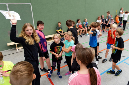 Eine der Sporthelferinnen, die das Bewegungsspektakel organisieren, sucht ihre Gruppe unter dem Faultier-Sid-Plakat zusammen. (Foto: Alfred Riese) Eine der Sporthelferinnen, die das Bewegungsspektakel organisieren, sucht ihre Gruppe unter dem Faultier-Sid-Plakat zusammen. (Foto: Alfred Riese)