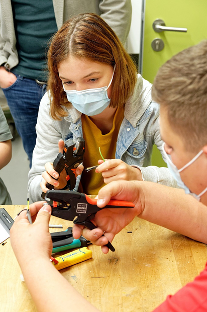 Mit den Basics fängt es an: Eine Achtklässlerin sieht sich bei der Mint-Rallye während der Projektwoche an der MKG bei einem Azubi der Ibbenbürener Firma Keller HCW an, wie man ein Kabel ordentlich abisoliert. Foto: Alfred Riese