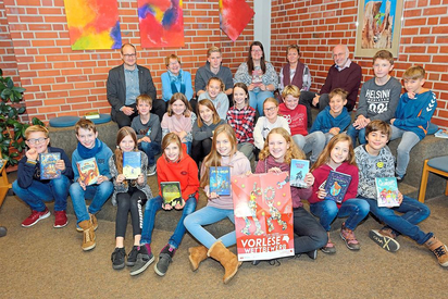 Leni Wernsmann (links vom Plakat), Siegerin des Vorlese-Wettbewerbs an der MKG, mit den sieben weiteren Finalisten aus dem sechsten Jahrgang, deren Begleitern, der Jury (hinten) und Maarten Willenbrink, stellvertretender MKG-Leiter (hinten links). Foto: A