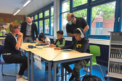 Christiane Althoff (li.), Maarten Willenbrink (hinten) und Niels Effelsberg freuen sich mit den jungen Schülern über die neue Möglichkeit der digitalen Förderung. Die drei Jungs übrigens müssen keine Maske tragen - es sind Brüder. Foto: Martin Weßeling 
