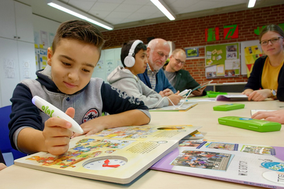 Momen, Schüler mit Deutsch als Zielsprache an der MKG, probiert einen der neuen Bookii-Hörstifte mit dem Buch aus. Foto: Alfred Riese 